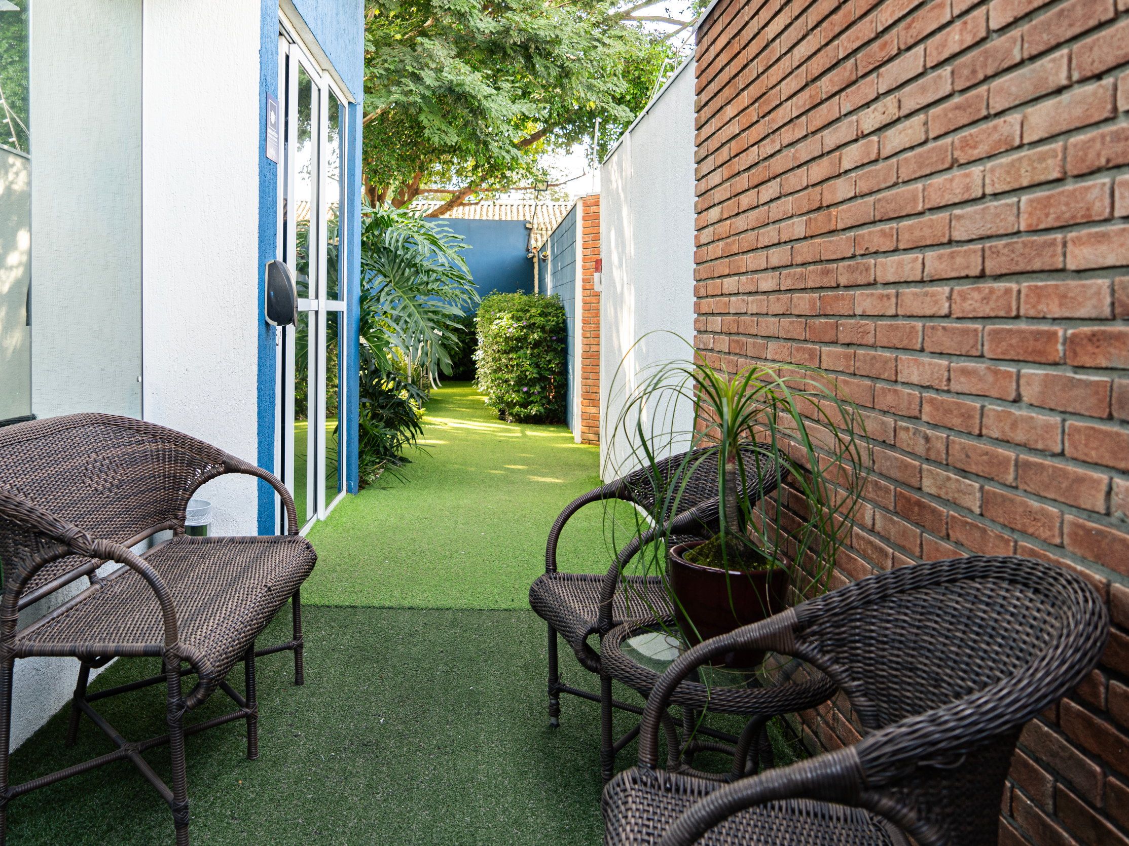 Corredor de tijolo à vista com poltronas, no Residencial Espaço Saúde