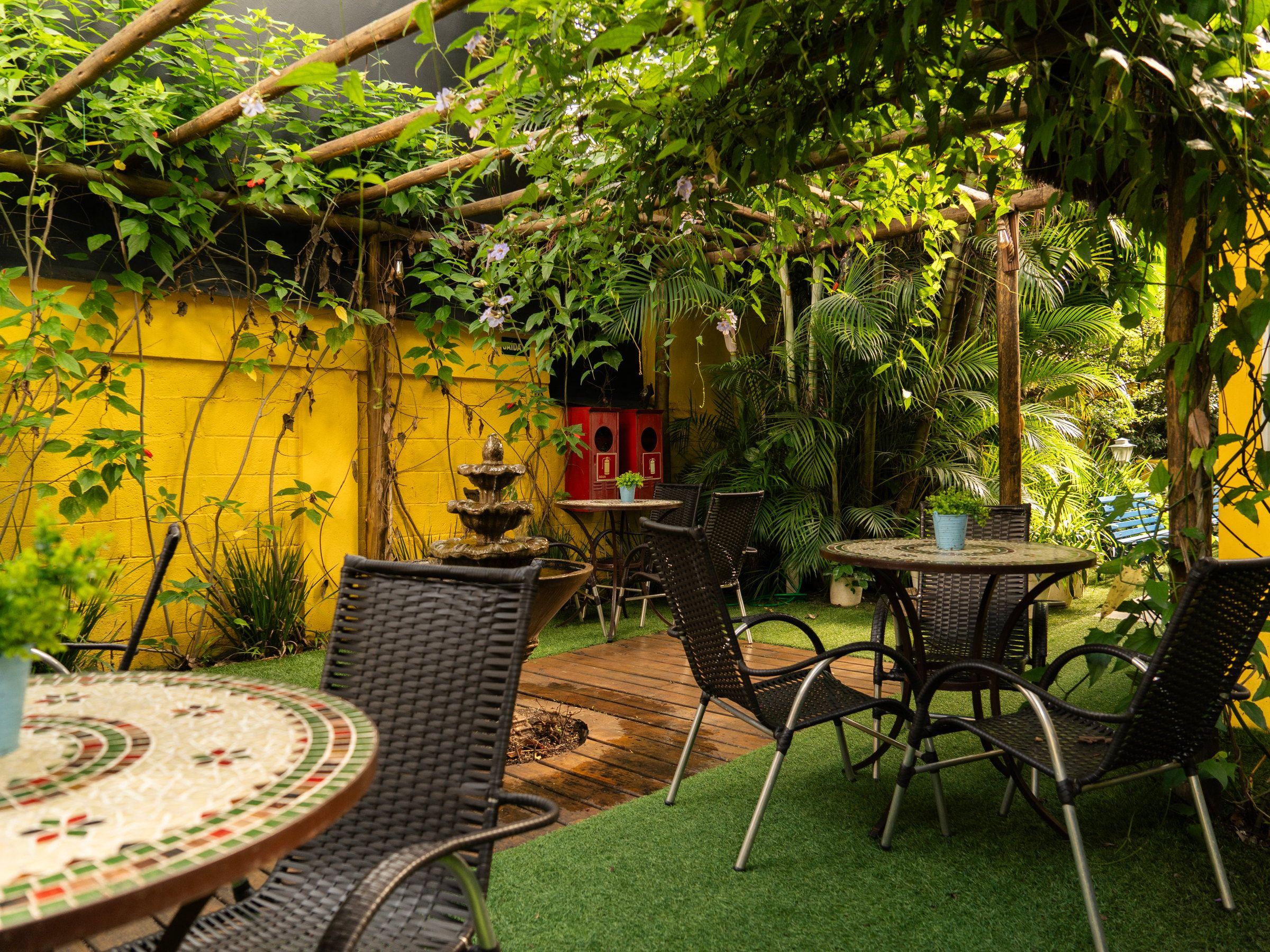 Deck da Kûara com mesa de mosaico, cadeiras e o chafariz ao fundo