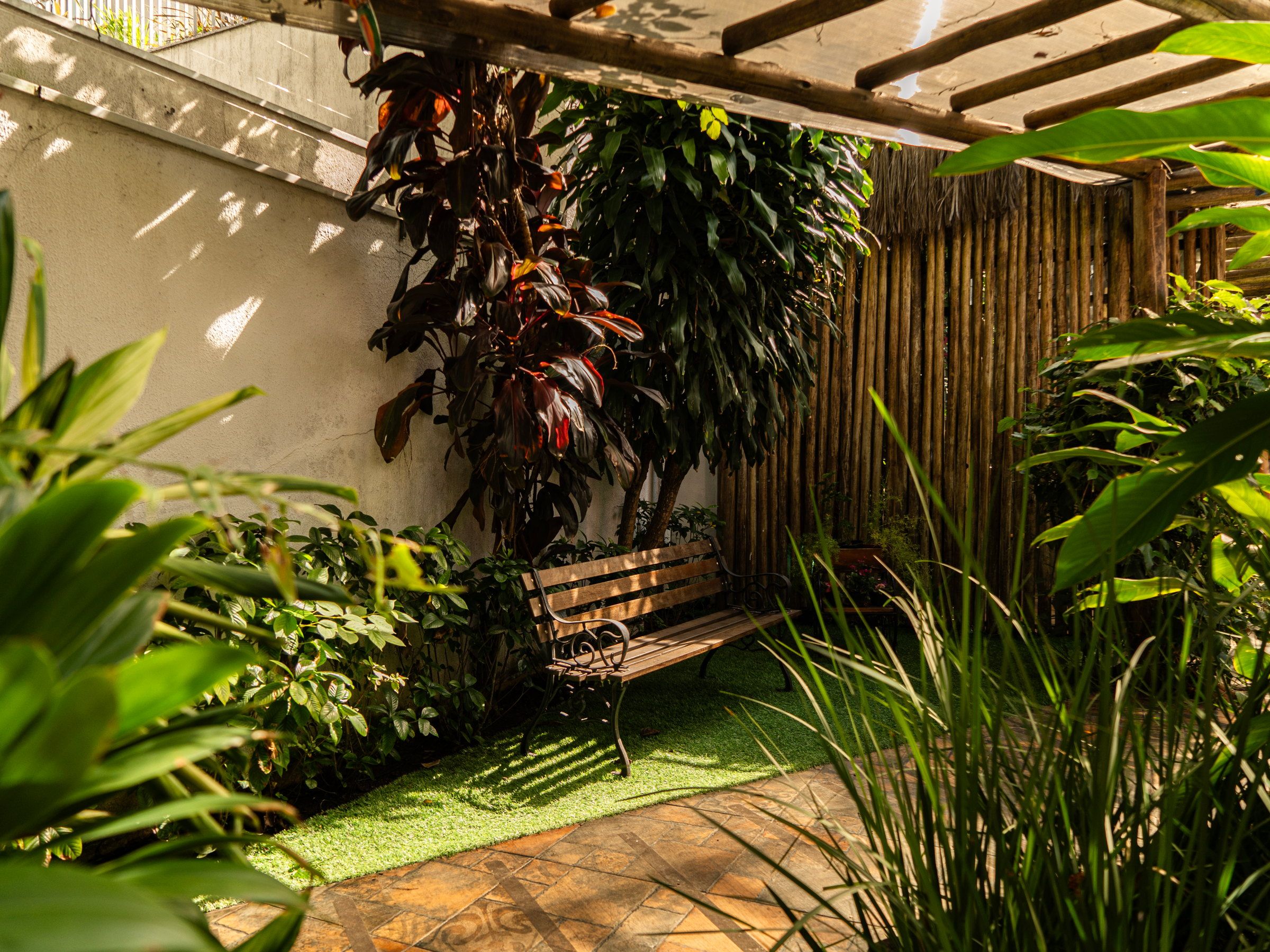 Banco de madeira entre plantas, sob o pergolado do jardim da La Vie