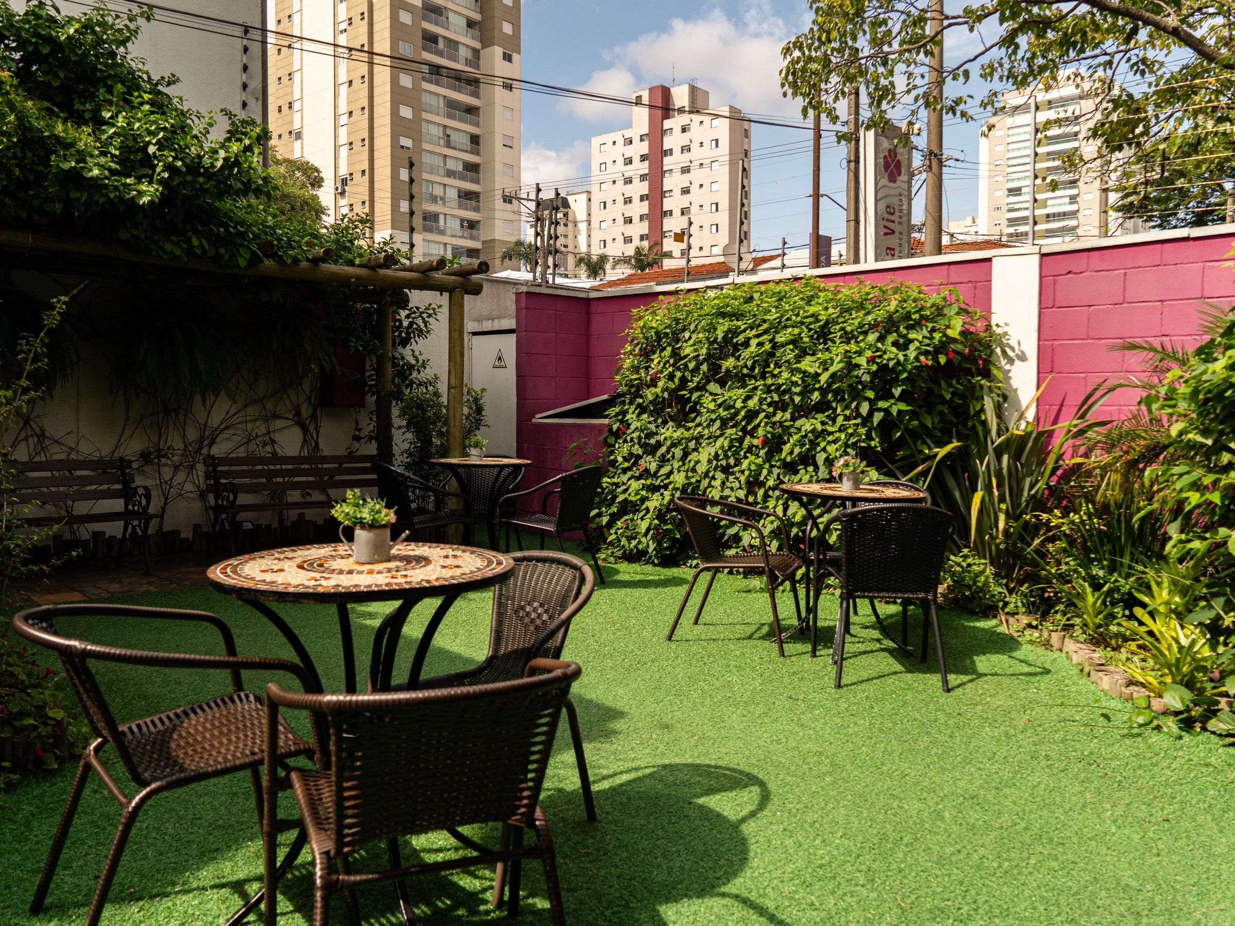 Jardim da La Vie com mesa, cadeiras e muro coberto de plantas