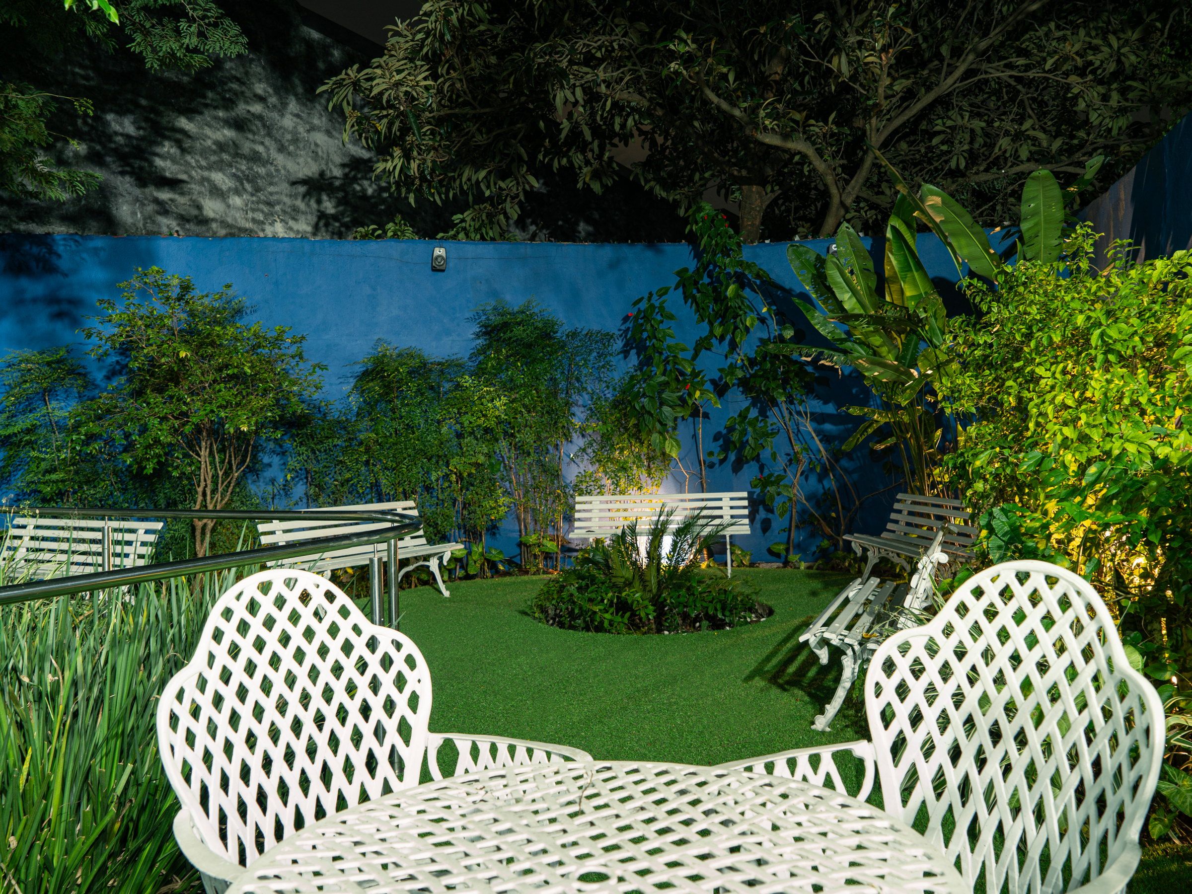 Mesa e cadeiras brancas no jardim do Residencial Espaço Saúde, à noite